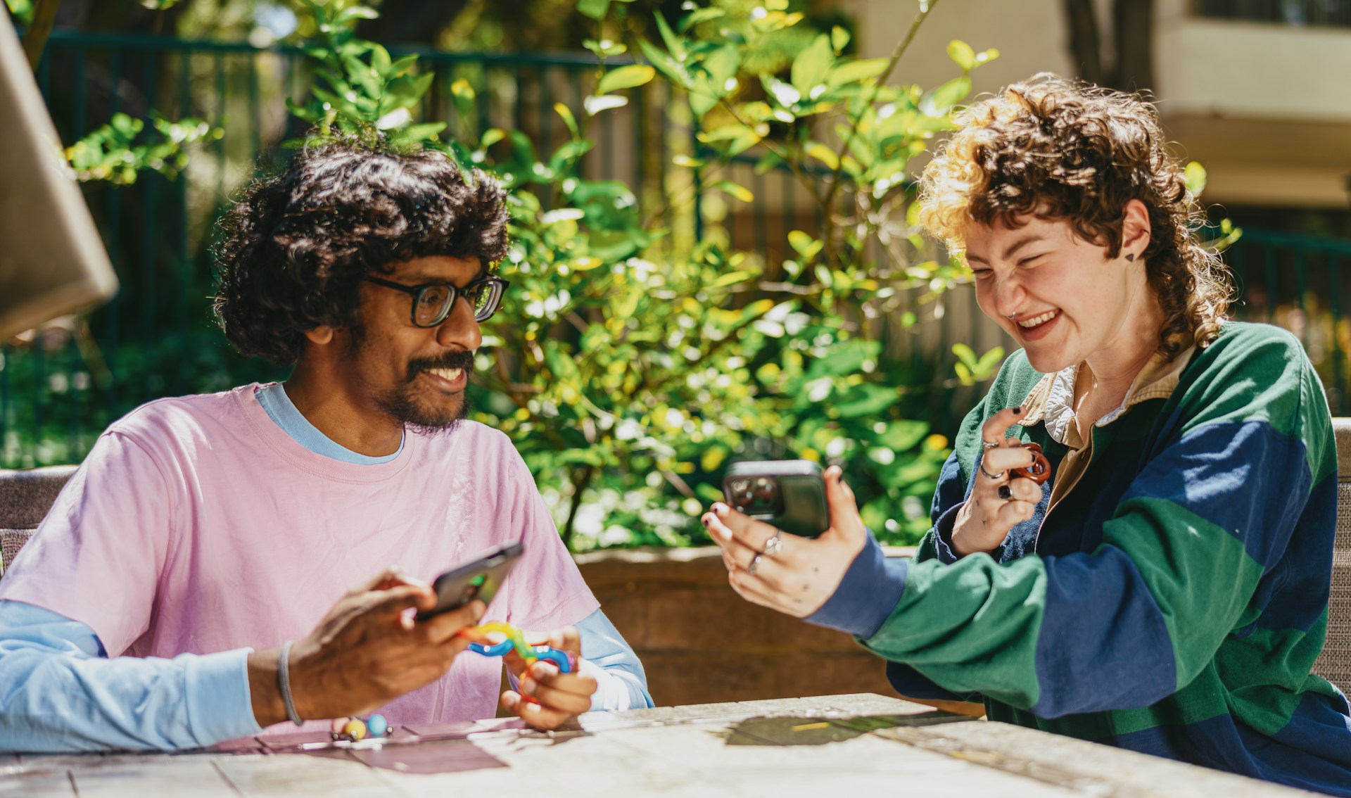 A man and women sitting outside on their phones